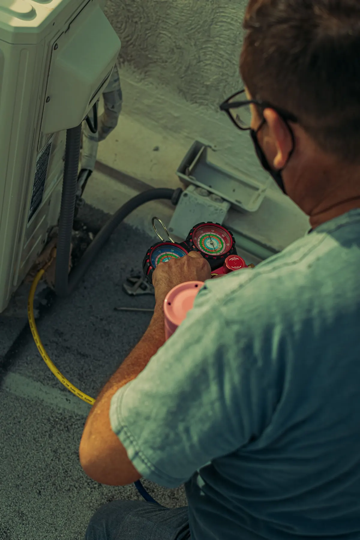Technician reading refrigerant gauges on an air conditioner