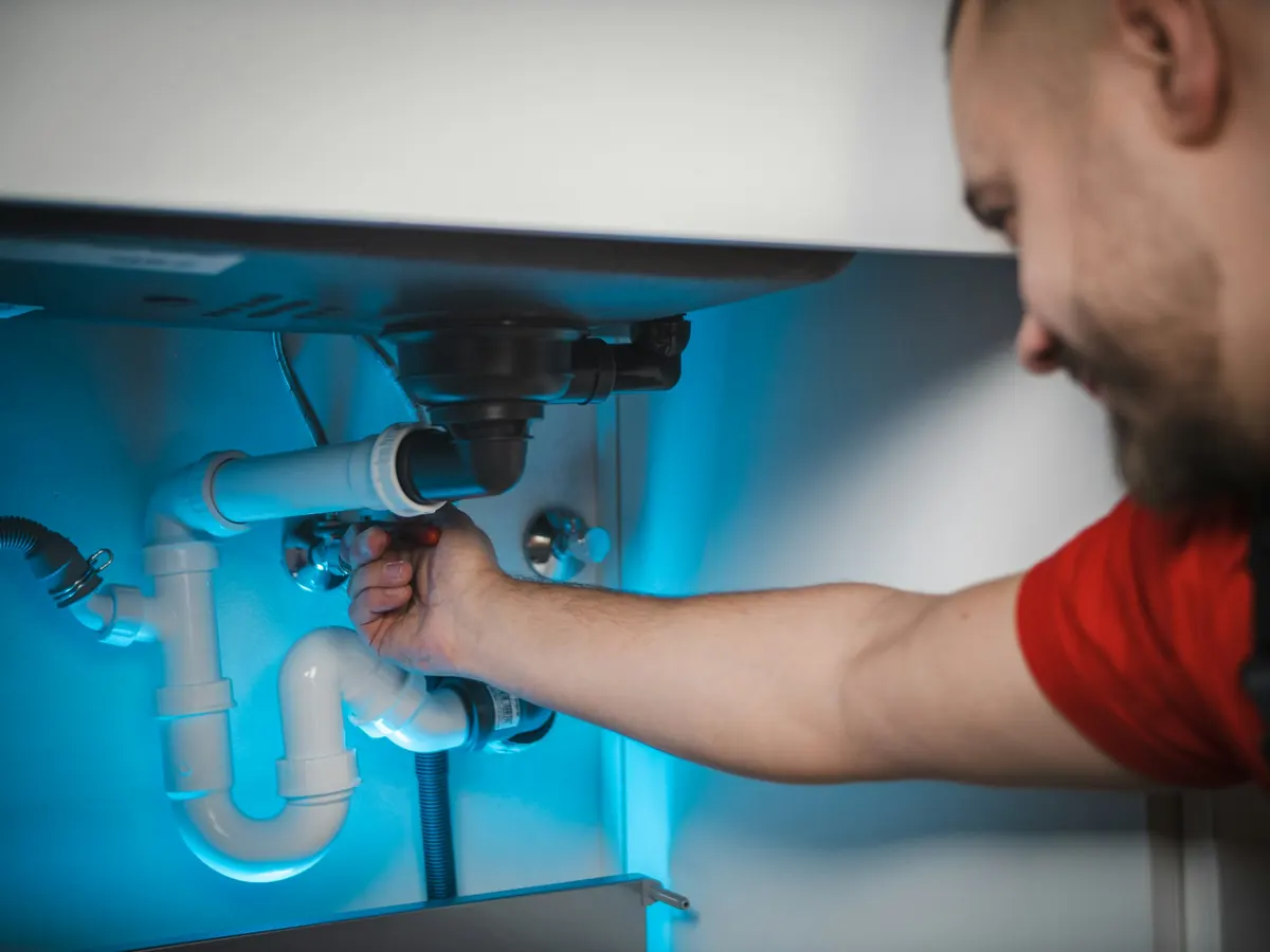 Plumber fitting a drain pipe under a sink